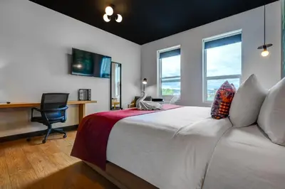 a bedroom with a bed with a desk and windows at Raven Inn Whitehorse in Whitehorse