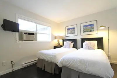 two beds in a room with a window and a tv at Glacier's Reach by Whistler Retreats in Whistler