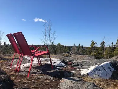 a red chair sitting on a pile of rocks at \u597d\u4e18\u3002Hacho House in Yellowknife