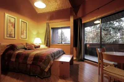 a bedroom with a bed and a table and a window at Rainbow Suites by Whistler Retreats in Whistler