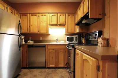 a kitchen with wooden cabinets and a stainless steel refrigerator at Rainbow Suites by Whistler Retreats in Whistler