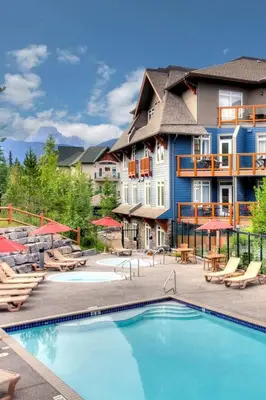 a resort with a swimming pool and chairs and a building at Luxurious & Spacious Mountain Retreat in Canmore