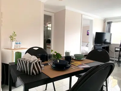 a dining room table with chairs and a table and a television at Perfect Location - Entire Suite Private Entrance with private bathroom & living room - 5 Mins Walk to Skytrain & Restaurant & Banks, 2 Stops To Metrotown, 5 Stops To Downtown in Vancouver
