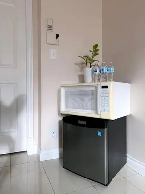 a microwave sitting on top of a black refrigerator at Perfect Location - Entire Suite Private Entrance with private bathroom & living room - 5 Mins Walk to Skytrain & Restaurant & Banks, 2 Stops To Metrotown, 5 Stops To Downtown in Vancouver