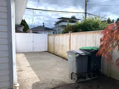 two trash cans in a driveway next to a fence at Perfect Location - Entire Suite Private Entrance with private bathroom & living room - 5 Mins Walk to Skytrain & Restaurant & Banks, 2 Stops To Metrotown, 5 Stops To Downtown in Vancouver