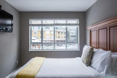 a bedroom with a white bed and a window at Whistler Blackcomb Vacation Rentals - Village North in Whistler