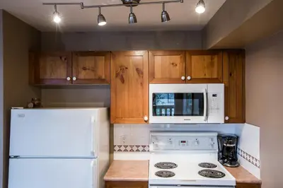 a kitchen with white appliances and wooden cabinets at Whistler Blackcomb Vacation Rentals - Village North in Whistler