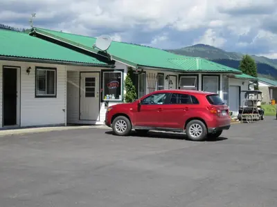 a red car parked in front of a building at Mountain Springs Motel & RV Park in Barrière