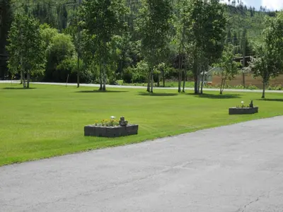 a park with people sitting on benches in the grass at Mountain Springs Motel & RV Park in Barrière
