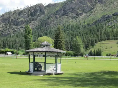 a gazebo in a field with a mountain at Mountain Springs Motel & RV Park in Barrière