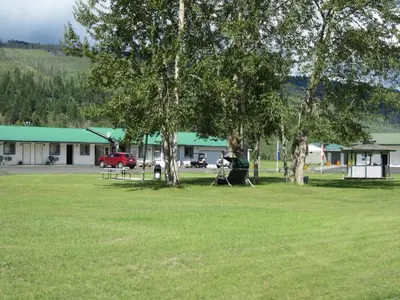 a park with trees in front of a building at Mountain Springs Motel & RV Park in Barrière