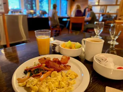 a plate of breakfast food on a table with orange juice at Park Place Lodge in Fernie