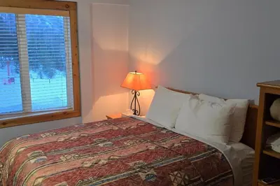 a bedroom with a bed with a lamp and a window at Cornerstone Lodge by Park Vacation Management in Fernie