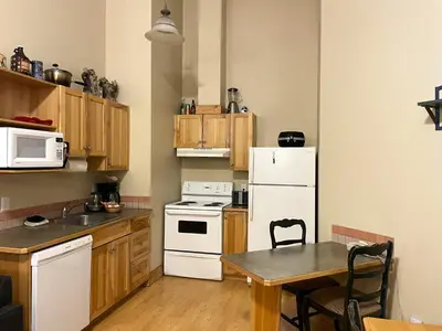 a small kitchen with a table and a white refrigerator at Cornerstone Lodge by Park Vacation Management in Fernie