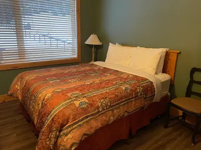 a bedroom with a bed and a window and a chair at Cornerstone Lodge by Park Vacation Management in Fernie