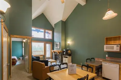 a kitchen and living room with green walls and tables at Cornerstone Lodge by Park Vacation Management in Fernie