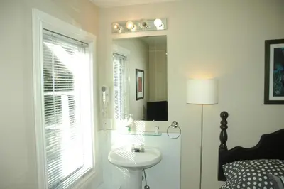 a white bathroom with a sink and a mirror at Cambie Lodge in Vancouver
