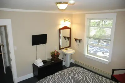 a bathroom with a bed and a sink and a mirror at Douglas Guest House in Vancouver