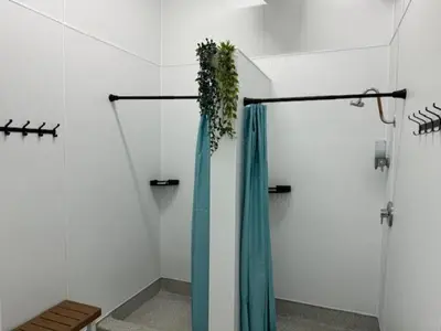 a shower with a blue shower curtain and a plant at HI Vancouver Jericho Beach - Hostel in Vancouver