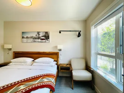 a bedroom with a bed and a window and a chair at Joe's Contemporary 2 King Bedrooms Vacation Home in Canmore in Canmore