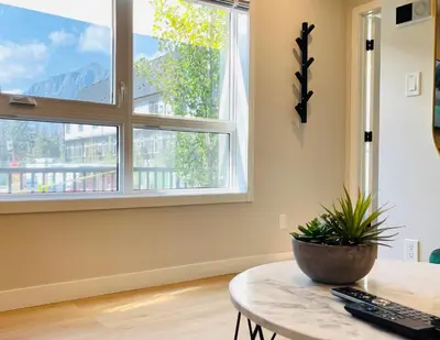 a living room with a table and two windows at Joe's Contemporary 2 King Bedrooms Vacation Home in Canmore in Canmore