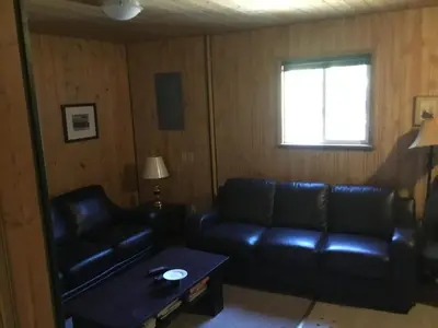 a living room with a leather couch and a table at Barney’s Lakeside Resort in Puntzi Lake