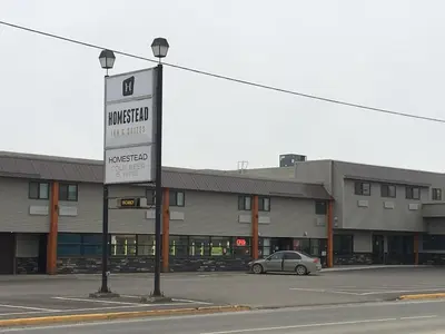 a car parked in a parking lot in front of a building at Homestead Inn & Suites in Vanderhoof
