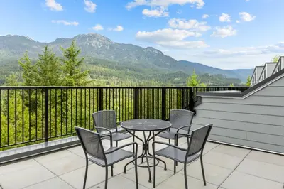 a patio with a table and chairs on a balcony with mountains at Worldmark Whistler Sundance in Whistler