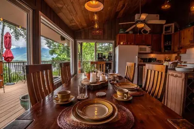 a dining room with a table and a kitchen at The Fraser River's Edge B&B Lodge in Chilliwack