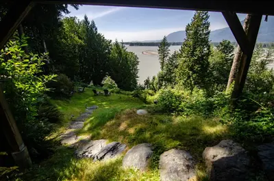 a view of a lake with rocks and trees at The Fraser River's Edge B&B Lodge in Chilliwack