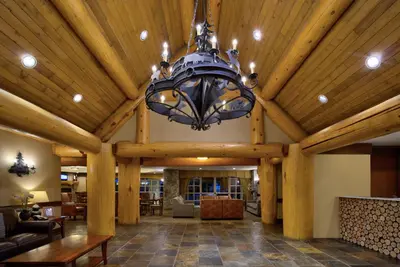 a large living room with a chandelier hanging from a wooden ceiling at Blackcomb Springs Suites by CLIQUE in Whistler