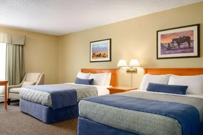 a hotel room with two beds and a chair at Travelodge by Wyndham Edson in Edson