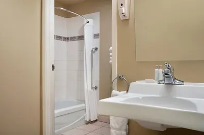a white bathroom with a sink and a tub at Travelodge by Wyndham Edson in Edson