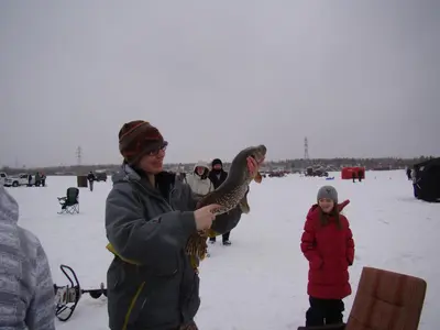 a woman holding a peacock in the snow with a child at Shoreside Inn & Suites in Wabamun