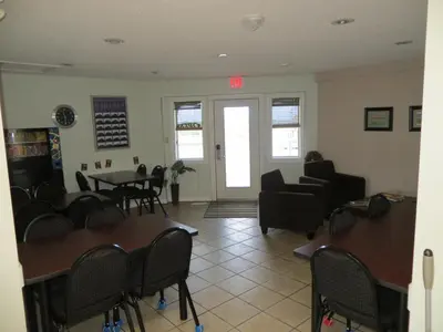 a waiting room with chairs and tables and a door at Shoreside Inn & Suites in Wabamun
