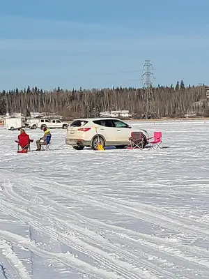 two people sitting in chairs in a snow covered parking lot at Shoreside Inn & Suites in Wabamun