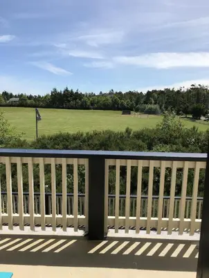 a balcony with a view of a golf course at Pacific Rim Guest Lodge - Adults Only in Ucluelet