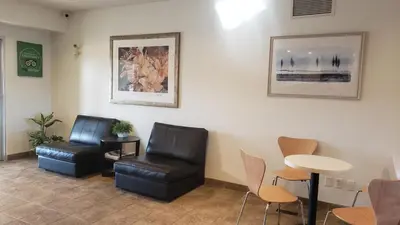a waiting room with two chairs and a table at Joys Inn Innisfail, AB in Innisfail