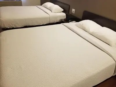 two beds in a room with white sheets and pillows at Joys Inn Innisfail, AB in Innisfail