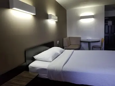 a bedroom with a bed and a chair and a table at Joys Inn Innisfail, AB in Innisfail