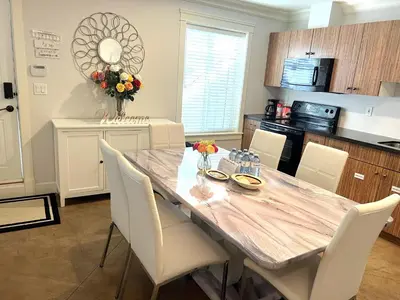 a kitchen with a dining room table with white chairs at Hannah's Heavenly Home in Surrey