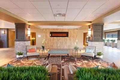 a lobby with a table and chairs in a building at Pomeroy Inn & Suites at Olds College in Olds