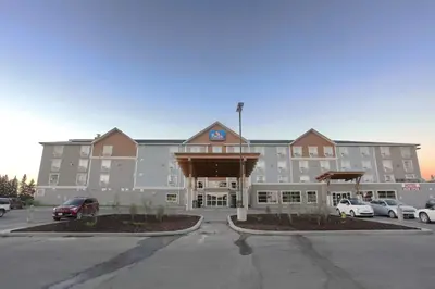a large hotel with a parking lot in front of it at Pomeroy Inn & Suites at Olds College in Olds