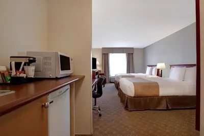 a hotel room with two beds and a desk with a television at Days Inn by Wyndham Dawson Creek in Dawson Creek