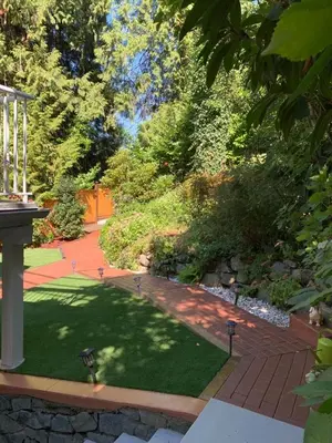 a garden with green grass and a brick pathway at Beautiful Two Bedroom Suite in North Vancouver