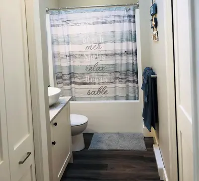 a bathroom with a toilet and a shower curtain at Sandy Feet Retreat Port Renfrew- Oceanfront 2BR modern cottage in Port Renfrew