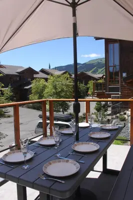 a table with glasses and an umbrella on a balcony at Woodhaven # 8 in Sun Peaks in Sun Peaks