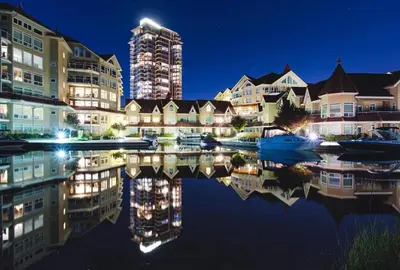 a city with buildings and a reflection in the water at Kelowna Discovery in Kelowna