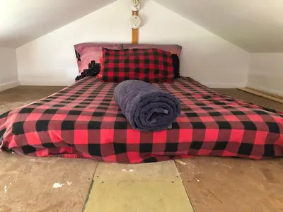 a bed with a red and black checkered blanket at Cabine, Home Sweet Home in Whitehorse