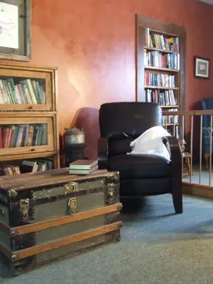 a living room with a chair and a book shelf with books at Country Encounters Accommodations in Coleman